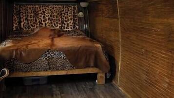 A room with a bed, a leopard print headboard, and wooden walls.