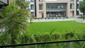 A modern building with a courtyard featuring green grass and palm trees.