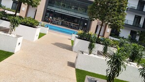 A modern building with a swimming pool, surrounded by landscaped areas with trees and planters.