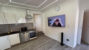 Una cocina moderna con electrodomésticos de acero inoxidable, un televisor de pantalla plana montado en la pared y suelo de madera.