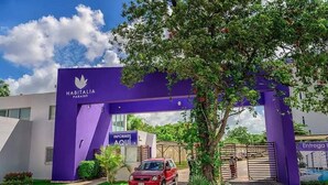 A purple archway with 'Habitália Paraíso' signage, a red car parked in front, and a tree to the right. - Deluxe 2 Bed 2 Bath Condo with a (Large outdoor Pool/Hot Tub) (Cancún)