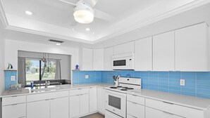 Une cuisine moderne avec des meubles blancs, un four à micro-ondes encastré et une cuisinière à gaz.