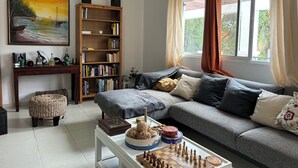 A living room with a sofa, a bookshelf, a painting, and a chessboard.