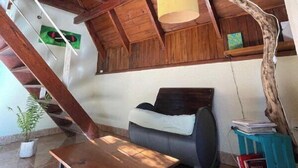 A room with a wooden ceiling, a sofa, a table, and a lamp. - Bungalow hostel Iguazù (Puerto Iguazú)