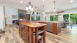 A spacious kitchen with wooden cabinets, a large island, and pendant lighting. - Lakefront: Hot tub, Dock, Firepit, Kayaks, Grill, Sleeps 13 (Henrico)