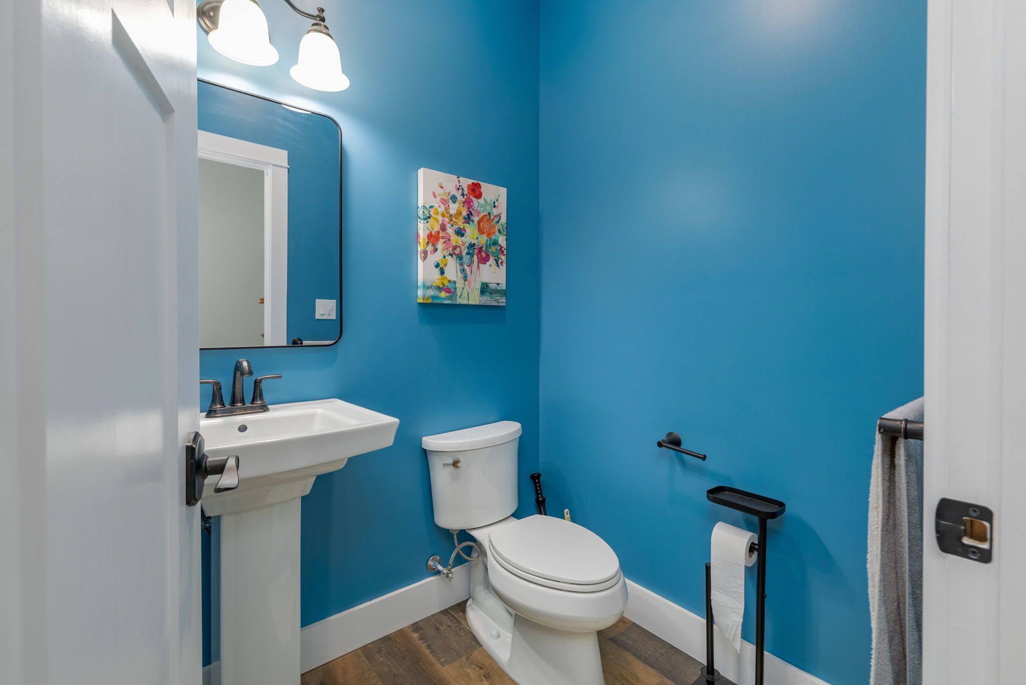 A bathroom with a white sink, a toilet, and a blue wall.