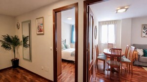 A room with a wooden floor, a bed, a dining table with chairs, and a sofa. - Llanes Delux Apartment (Llanes)
