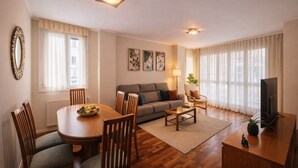A modern living room with a dining table, sofa, and TV. - Llanes Delux Apartment (Llanes)