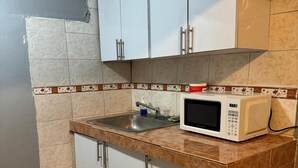 Une cuisine avec des meubles blancs, un four à micro-ondes et un évier.