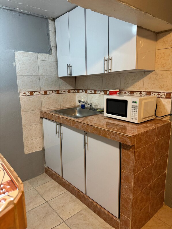 Una cocina con armarios blancos, un microondas y un lavabo.