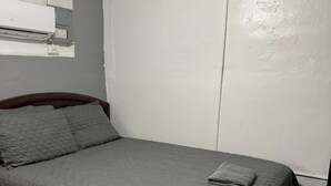 Une chambre à coucher avec un lit, un climatiseur fixé au mur et une porte.