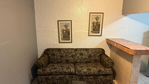 Une pièce avec un canapé à motifs, une petite table ronde et deux tableaux encadrés accrochés au mur.