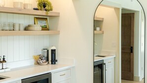 Une cuisine moderne avec des meubles blancs, un four encastré et un grand miroir.
