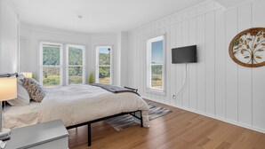 A bedroom with a bed, bedside table, lamp, and a TV mounted on the wall.