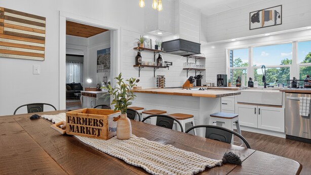 A modern kitchen with white cabinetry, wooden countertops, and a farmhouse-style dining area.