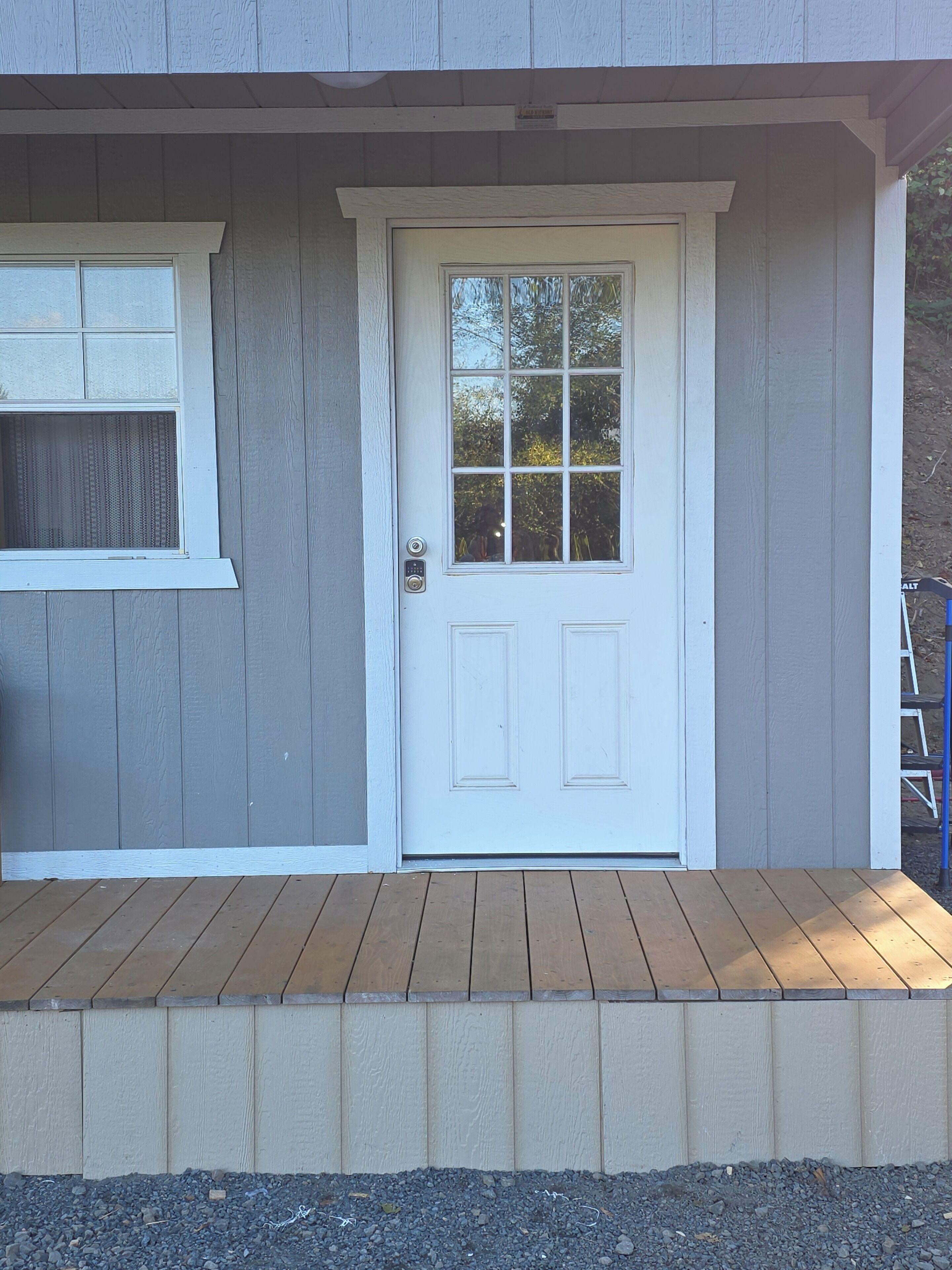 A house with a white front door, a window with a white frame, and a wooden deck.