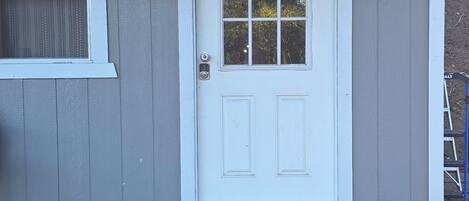 A house with a white front door, a window with a white frame, and a wooden deck.