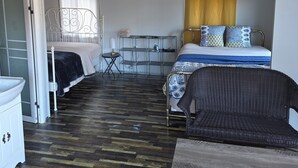 Quarto compacto com cama, uma cadeira, uma mesinha e um armário branco.