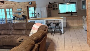 En ombonad träinredning med en soffa i läder, ett köksområde och ett matbord.