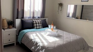 A neatly arranged bedroom with a bed, bedside table, and a hanging light fixture.