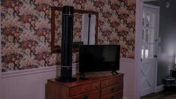 Ein Schlafzimmer mit Fernseher auf einer Kommode, einer Tür und blumigem Wandpapier.