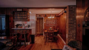 Uma cozinha acolhedora com armários de madeira, um espaço de jantar com mesa e cadeiras, e uma sala de estar com sofá de couro.