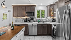 A modern kitchen with dark wood cabinets, stainless steel appliances, and a marble backsplash. - Near pool & beach. Private Hot Tub. AC, Firepit (Pocono Lake)