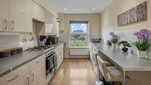 Une cuisine moderne avec vue sur l’extérieur, comprenant des meubles de rangement, une cuisinière et une fenêtre.