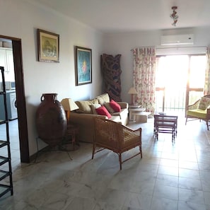 Un salon avec un canapé, un grand vase, une lampe et un ventilateur de plafond.