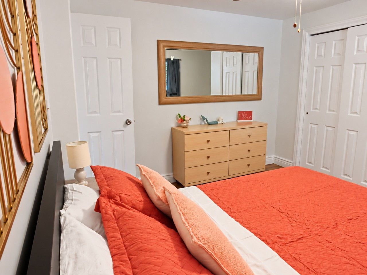 Een slaapkamer met een bed, een kaptafel, een spiegel en een deur.