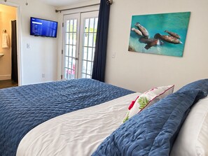 A bedroom with a bed, a television on the wall, and a painting of dolphins.