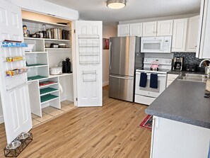 A compact kitchen with white cabinetry, a stainless steel refrigerator, a microwave, and a stove.
