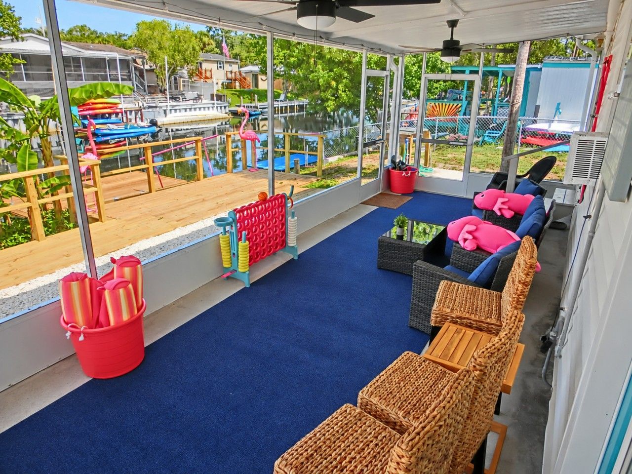 A covered outdoor seating area with wicker furniture and a red bucket of utensils.