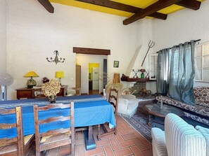 A dining area with a table set for two, a sofa, and a small table with a lamp.