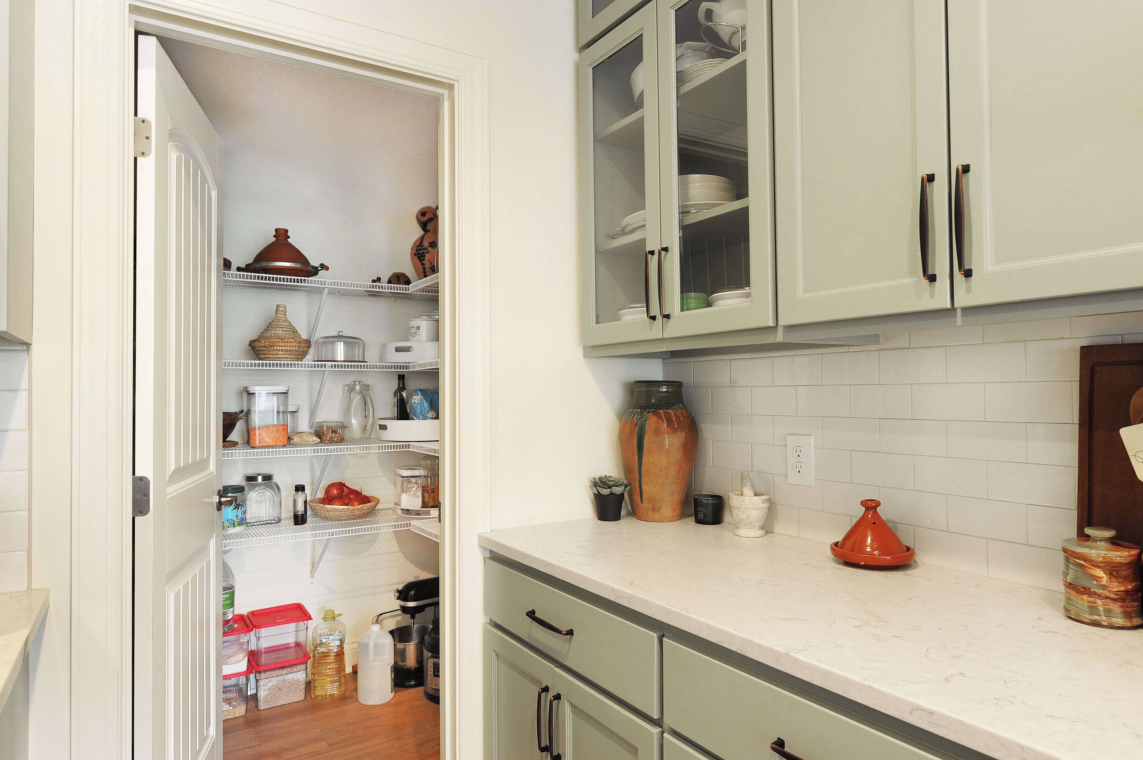 A kitchen with white cabinets, a countertop, and a variety of kitchenware and appliances.