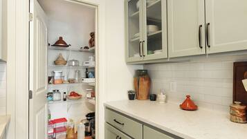 A kitchen with white cabinets, a countertop, and a variety of kitchenware and appliances.