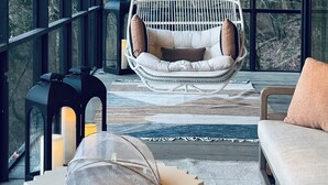 A modern interior with a hanging chair, a sofa, and a table with a transparent dome. - *NEW* Waterfront Treehouse - Sweeping Views on 2.5 Acres (Knoxville)