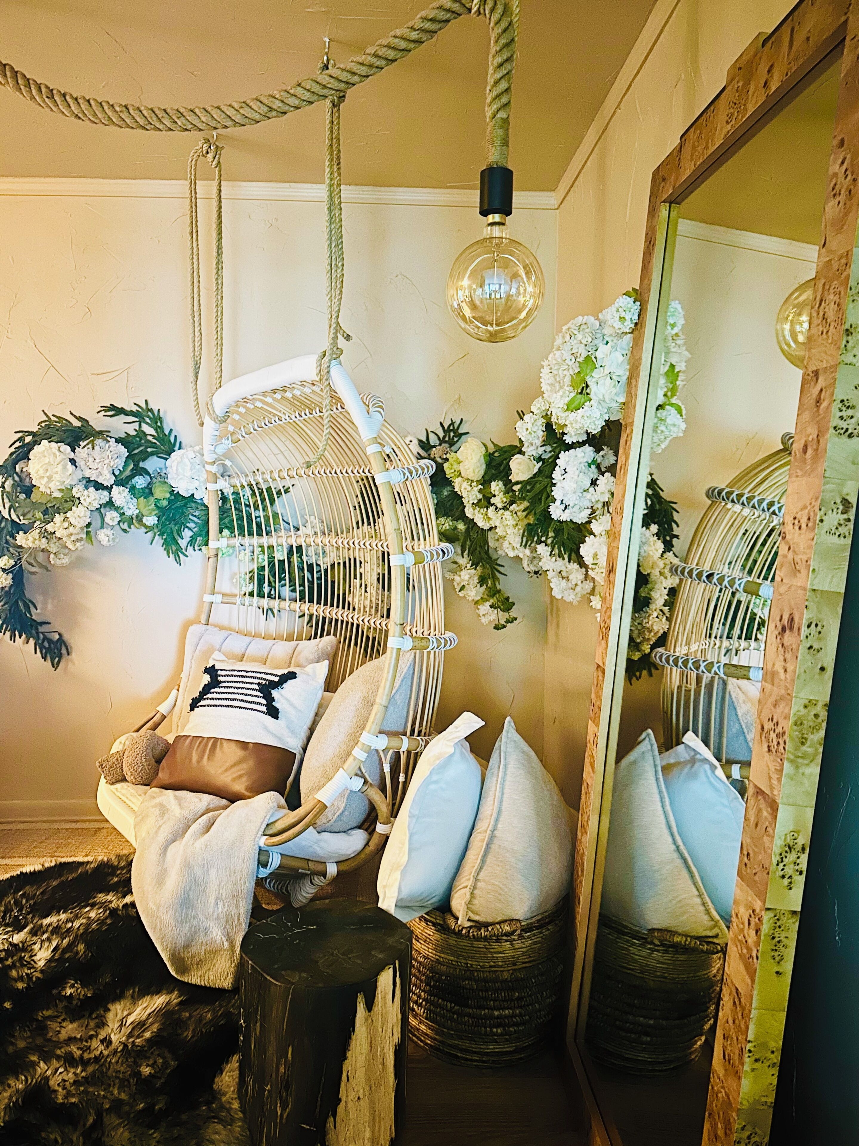 Um quarto aconchegante com uma cadeira suspensa, um espelho e detalhes florais.
