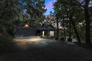 Une maison avec un garage, entourée d’arbres et dotée d’une allée.