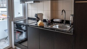 A modern kitchen with dark cabinets, a stainless steel sink, and a built-in oven. - 3BR Flat by Casa da Música | Central, Sleeps 6 | D (Porto)