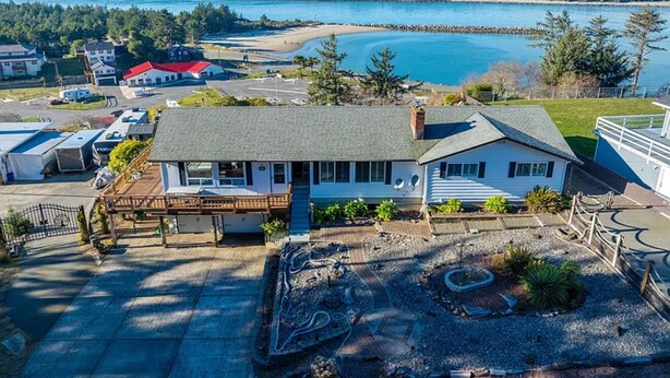 A house with a large deck, a hot tub, and a view of the ocean.