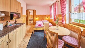 Una habitación acogedora con una cama, una mesa de comedor y una zona de cocina con armarios de madera y un microondas.