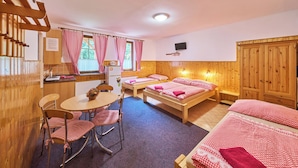 A cozy room with wooden walls and furniture, a small kitchen area, and a bed with checkered bedding.