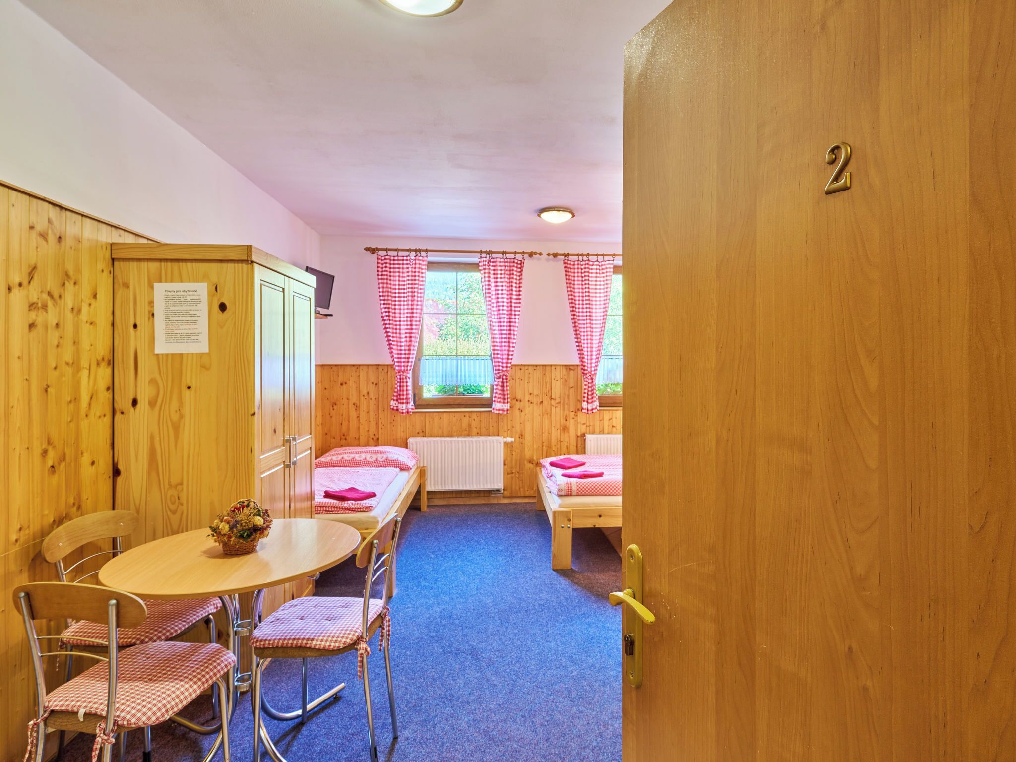 A cozy room with wooden walls, a round table with chairs, and two beds.