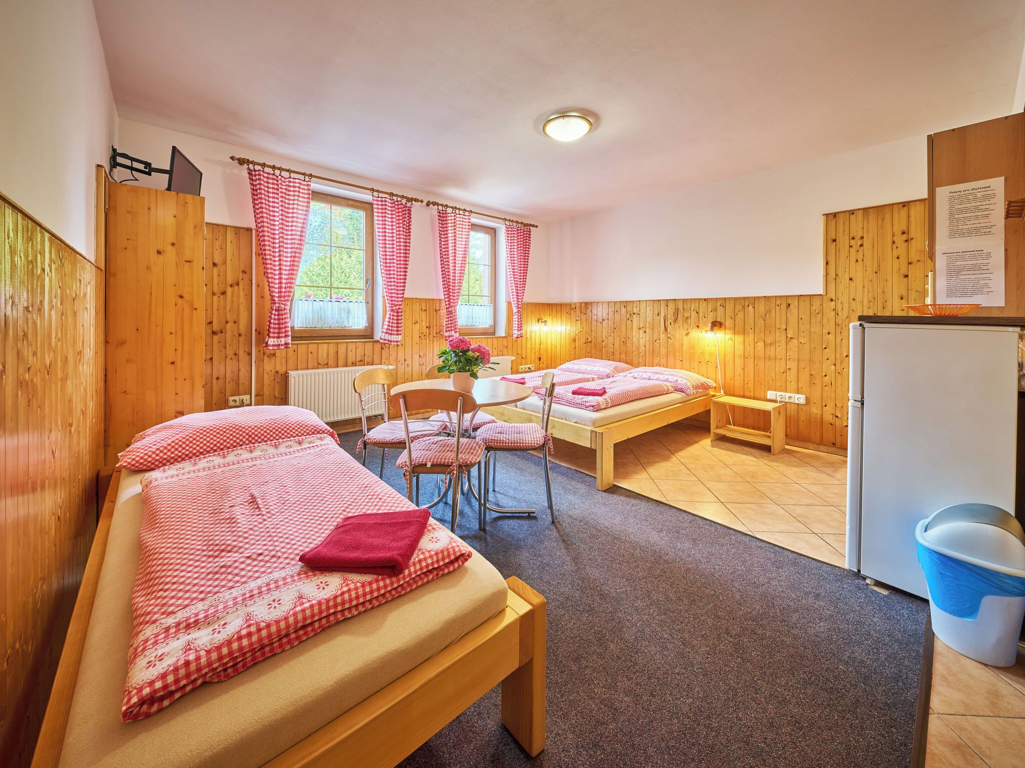 Une chambre confortable avec deux lits, une petite table et un réfrigérateur.