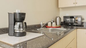 Eine Küchenzeile mit Kaffeemaschine, Wasserkocher, Mikrowelle und Spüle.