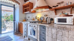 A kitchen with a stone backsplash, wooden cabinets, a stove, and a microwave. - Vacation home Petra by Interhome (Umag)