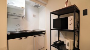 A compact kitchenette with a microwave, kettle, and small refrigerator.