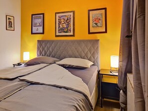 Una cama con colcha, dos mesitas de noche con lámparas y tres cuadros en la pared.