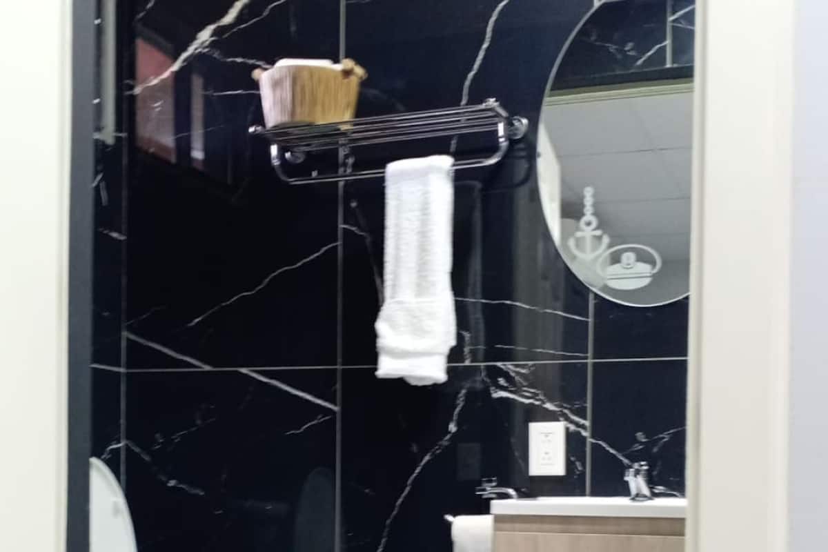 A bathroom with a toilet, a sink, a mirror, and a towel rack.